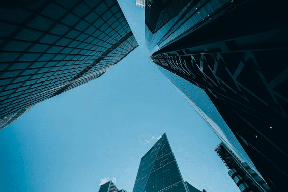 Supreme Court Rules: Looking up at modern skyscrapers with reflective glass facades against a clear blue sky.